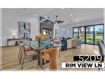 Modern living room with a glass dining table, linear fireplace, and light wood floors at 5209 Rim View Ln, Las Vegas, NV 89130