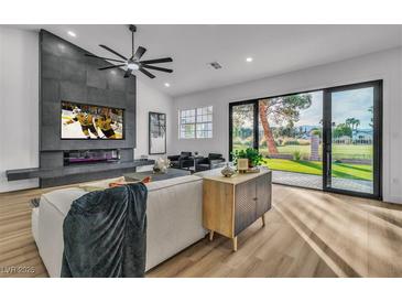 Bright living room featuring a modern fireplace, ceiling fan, and sliding glass doors to the backyard at 5209 Rim View Ln, Las Vegas, NV 89130