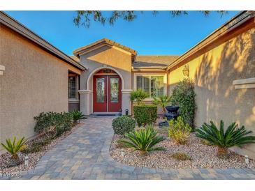 Charming front entrance showcasing a red door, beautiful landscaping and paved walkway at 6156 Twilight Cove Cir, Las Vegas, NV 89131