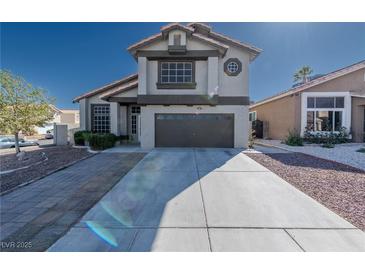 Two-story home with a desert landscape, wide driveway, and a two-car garage under a clear blue sky at 8869 Dove Cove Dr, Las Vegas, NV 89129