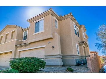 Two-story tan home with a two-car garage and manicured landscaping at 225 Priority Point St, Henderson, NV 89012