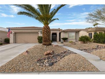 Inviting single-story home with a desert landscape featuring a palm tree and rock accents at 4557 Bersaglio St, Las Vegas, NV 89135