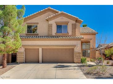 Two-story tan home featuring a two car garage and tile roof at 74 Harbor Coast St, Las Vegas, NV 89148