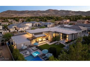 Stunning aerial view of a modern home with a pool, jacuzzi, and mountain views at 3452 Spanish Winds Ct, Las Vegas, NV 89141