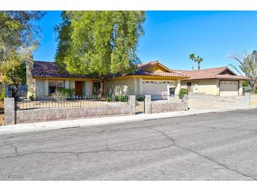 Charming single-story home featuring mature trees, a two-car garage, and a gated front yard at 3920 Aspencrest Dr, Las Vegas, NV 89108