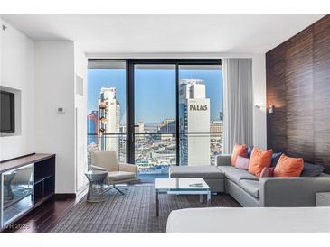 Bright living room featuring a modern sofa, expansive windows with a city view, and sleek furnishings at 4381 W Flamingo Rd # 2504, Las Vegas, NV 89103