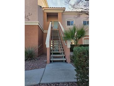 Inviting condo exterior featuring a staircase leading to a charming second-story entrance and desert landscaping at 10525 Autumn Pine Ave # 203, Las Vegas, NV 89144