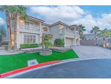 Charming two-story home showcasing lush landscaping, a paver driveway, and a three-car garage at 11002 Inverlochy Ct, Las Vegas, NV 89141