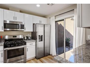 Modern kitchen with stainless steel appliances and white cabinets, featuring a sliding door to the patio at 2517 Desert Glen Dr, Las Vegas, NV 89134