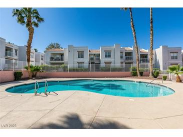 Inviting community pool with palm trees and well-maintained buildings under a clear blue sky at 6800 E Lake Mead Blvd # 1034, Las Vegas, NV 89156