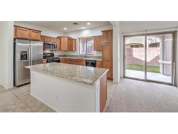 Well-lit kitchen with stainless steel appliances, granite countertops, and an island with backyard access at 6856 Pipil St, Las Vegas, NV 89166