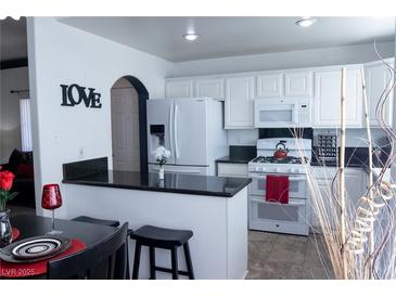 Eat-in kitchen featuring white cabinetry, black granite countertops, and modern appliances at 10553 Pine Pointe Ave # 201, Las Vegas, NV 89144