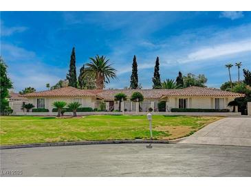Expansive front yard view of a single story home with lush landscaping and a circular driveway at 208 Stonewood, Las Vegas, NV 89107