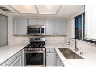 This kitchen features stainless steel appliances, white countertops, light gray cabinets, and a window at 7100 Pirates Cove Rd # 2065, Las Vegas, NV 89145