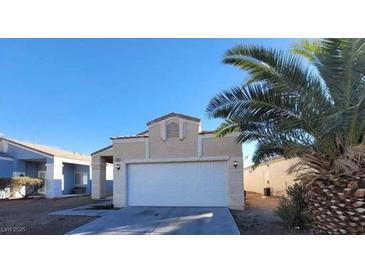 Beige single-Gathering home with a two-car garage, palm tree and low maintenance desert landscaping at 2100 Fred Brown Dr, Las Vegas, NV 89106