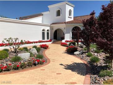 Stunning white home featuring a brick walkway, blooming flowers, and lush landscaping at 3938 E Russell Rd, Las Vegas, NV 89120