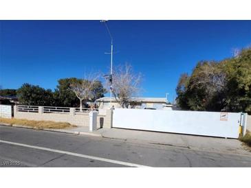 Exterior view of a single story home with a large white security gate at 4928 E Monroe Ave, Las Vegas, NV 89110