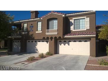 Modern townhome showcasing multi-car garage with a desert landscape and private balcony at 7290 Sheared Cliff Ln # 102, Las Vegas, NV 89149