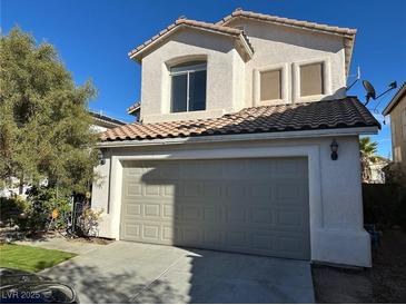 Two-story home features a neutral exterior, a two-car garage, a tile roof and tidy landscaping at 5758 Yellowcrest Ct, Las Vegas, NV 89113