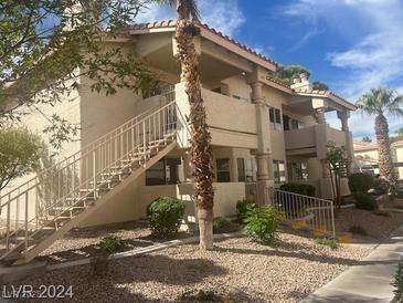 Two story condo with steps leading to the second floor units and desert landscaping at 924 Falconhead Ln # 102, Las Vegas, NV 89128