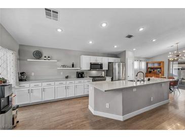 Bright kitchen features an island, stainless steel appliances, white cabinetry, and wood flooring at 1104 Christopher View Ave, North Las Vegas, NV 89032