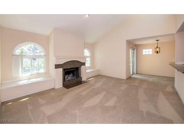 Cozy living room featuring a fireplace, neutral carpet, and arched windows with recessed seating at 3145 E Flamingo Rd # 2119, Las Vegas, NV 89121