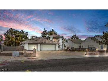 Two-story stucco home with a well-manicured lawn and mature trees at sunset at 3710 E Oquendo Rd, Las Vegas, NV 89120
