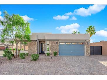 Charming single-story home featuring stone accents, manicured landscaping, and a blue garage door at 6325 Carmel Creek Ave, Las Vegas, NV 89139