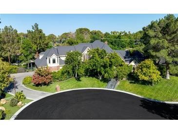 Expansive two-story home featuring a dark gray roof, beautiful landscaping, and mature trees at 3001 Astoria Pines Cir, Las Vegas, NV 89107