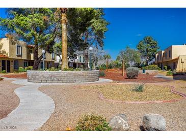 Charming townhomes surrounded by lush trees, rock features, and walkways on a sunny day at 431 Las Casitas Way, Las Vegas, NV 89121