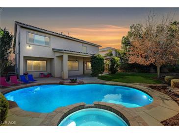 Backyard pool and hot tub with well-maintained lawn and colorful lounge chairs at 5148 Villa Vecchio Ct, Las Vegas, NV 89141