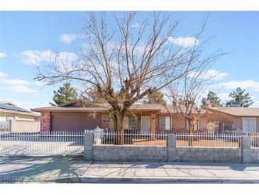 Charming single-story home featuring a gated front yard and neutral-tone exterior, topped by a vibrant blue, cloud filled sky at 849 Parkhurst St, Las Vegas, NV 89110