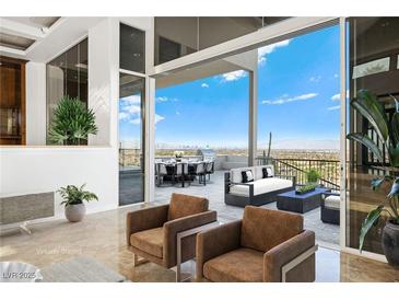 Bright living room featuring large sliding doors opening to an outdoor dining area with city views at 1484 Macdonald Ranch Dr, Henderson, NV 89012