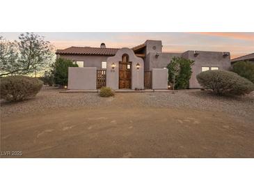 Charming stucco home with a beautiful wooden door and desert landscaping at 519 N Racetrack Rd, Henderson, NV 89015