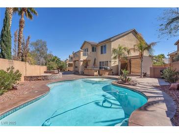 Resort-style backyard featuring a private pool, spa, built-in bar and lush landscaping at 2566 Antique Blossom Ave, Henderson, NV 89052