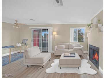 Bright living room features modern furniture, wood floors, fireplace, and sliding glass doors to outdoor space at 8600 W Charleston Blvd # 2098, Las Vegas, NV 89117