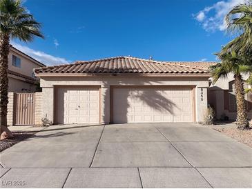 Tan home showcasing a two-car garage, desert landscaping, and a red tile roof, all under a bright blue sky at 8350 Campana Dr, Las Vegas, NV 89147