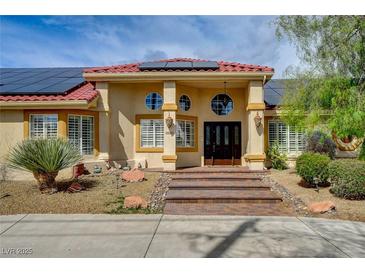 Inviting home featuring a terracotta roof, solar panels, and stone accents leading to the double-door entrance at 8880 W La Mancha Ave, Las Vegas, NV 89149