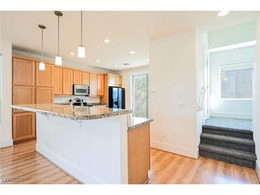 Bright kitchen featuring light wood cabinets, granite countertops, and a convenient breakfast bar at 9050 W Tropicana Ave # 1178, Las Vegas, NV 89147