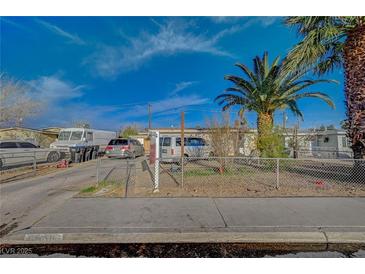 Modest single-story home featuring a chain-link fence, driveway, and various vehicles parked out front at 2716 Saint George St, North Las Vegas, NV 89030