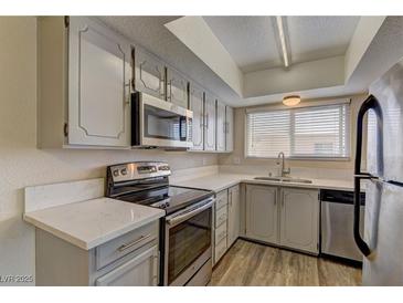 Updated kitchen features stainless steel appliances, white cabinets, modern countertops and laminate floors at 4666 Monterey Cir # 4, Las Vegas, NV 89169
