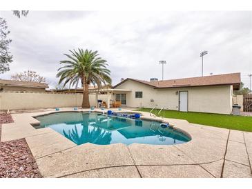 Backyard view of a sparkling pool with a palm tree, outdoor furniture and partially covered patio at 6309 Fairbanks Rd, Las Vegas, NV 89103