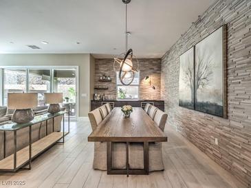 Open-concept dining room with a long wooden table, unique light fixtures, and a textured accent wall at 72 Reverie Heights Ave, Henderson, NV 89011