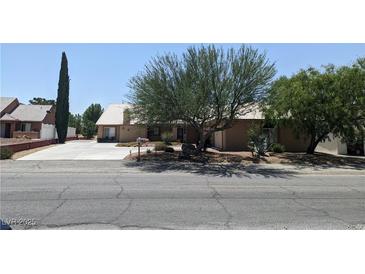 Charming single-story home with mature landscaping and a long driveway leading to an attached garage at 1211 Bourbon St, Pahrump, NV 89048