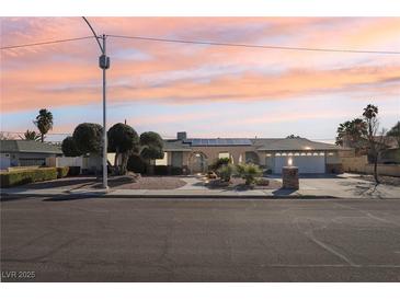 Charming single-story home with desert landscaping, solar panels, and a spacious two-car garage under a colorful sky at 1912 Parkchester Dr, Las Vegas, NV 89108
