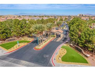 An impressive gated community entrance with lush landscaping, palm trees, and a beautiful entryway structure at 4372 Melrose Abbey Pl, Las Vegas, NV 89141