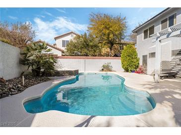 Sparkling in-ground pool with a tanning deck and mature landscaping, perfect for outdoor relaxation and entertaining at 6695 Shadow Cove Ave, Las Vegas, NV 89139
