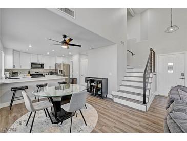 Bright living space featuring a modern staircase, open kitchen, and comfortable gray sectional at 1800 Montvale Ct, Las Vegas, NV 89134