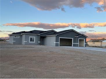 A charming single-story home boasting a three-car garage, against a backdrop of distant mountains and a serene sky at 2530 S Tecumseh Ave, Pahrump, NV 89048