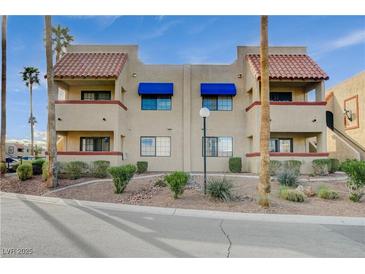 Condo complex showcasing a beige color scheme, blue awnings, and well-maintained landscaping at 4140 Gannet Cir # 255, Las Vegas, NV 89103
